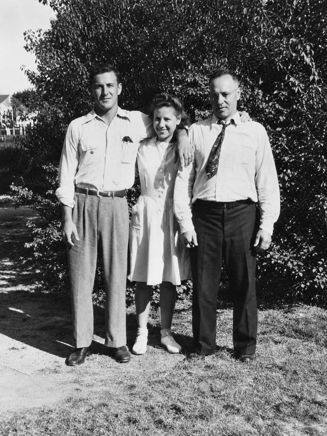 Black-and-white photograph, from left: Lucian, Wanda and their father, Teofil, standing on a lawn.